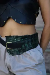 Cinturón ancho de cuero con textura de cocodrilo en tonos verde oscuro y negro, con hebilla metálica dorada.