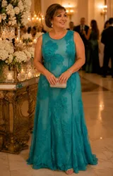 Vestido largo de fiesta color verde turquesa, confeccionado en tul con bordados de hilo de seda, canutillos y apliques florales en relieve. Presenta escote redondo, diseño sin mangas y falda con caída fluida y terminación con cola.