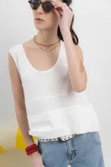 Musculosa blanca de algodón orgánico con escote en U, cortes irregulares y mezcla de texturas. Tiene un fit holgado y cinta aplicada en la espalda con bordado frutal.
