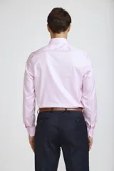 Camisa de vestir blanca de corte clásico, con cuello rígido, cierre frontal de botones y mangas largas con puños abotonados.