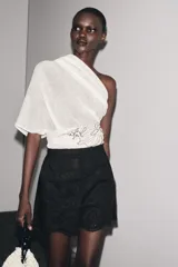 Bermuda negra de tiro alto confeccionada en hilatura de algodón con bordados perforados a tono, forro interior y cierre con cremallera oculta en costura.