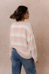 Buzo de tejido liviano con diseño de rayas horizontales en tonos amarillo manteca y blanco, cuello redondo y mangas largas con puños tejidos.