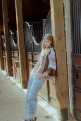 Sweater tejido en hilado 100% algodón con diseño a rayas verticales en tonos rojo, blanco, marrón y negro. Presenta flecos en el ruedo y bordados en el escote.