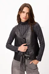 Chaleco de cuero negro con escote en V, cierre frontal con tiras de cuero y diseño de paneles horizontales.