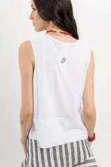 Musculosa blanca de algodón orgánico con escote en U, cortes irregulares y mezcla de texturas. Tiene un fit holgado y cinta aplicada en la espalda con bordado frutal.
