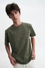 Remera verde militar con estampado de hojas en tono más oscuro, de manga corta, cuello redondo y corte regular.
