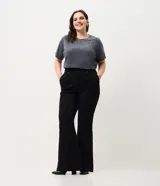 Pantalón de jean corte flare color negro, con cintura estructurada, bolsillos funcionales y recortes frontales con remaches brillantes.