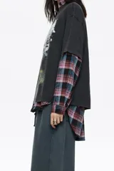 Camiseta negra de corte oversize con cuello redondo y mangas cortas. Presenta un estampado gráfico grande en el frente que simula un paisaje nocturno o crepuscular con un ciervo, árboles y montañas.