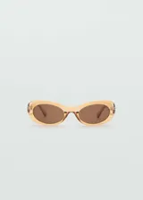 Gafas de sol con diseño ovalado y montura de pasta en color ámbar translúcido. Cuentan con cristales oscuros con protección UV categoría 3.