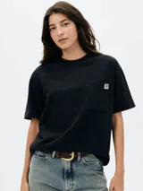 Remera de algodón color negro, de corte holgado y manga corta. Presenta un bolsillo frontal en el pecho con una pequeña etiqueta decorativa.