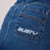 Pollera corta de jean, color azul medio, con tiro medio/bajo y corte recto. Presenta cinco bolsillos estilo jean y cierre de botón y cremallera.