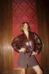 Campera de cuero marrón con cuello solapa, corte holgado y cierre frontal con un botón.