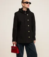 Saco corto negro de polivelour con capucha, cuello alto con cremallera, abotonado delantero cruzado, bolsillos delanteros y mangas largas.