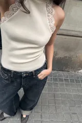 Top ajustado de tejido acanalado color crema, con cuello perkins y sisa adornada con aplicación de encaje a tono.