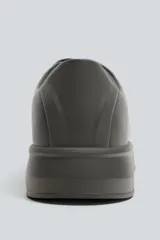 Zapatillas urbanas de cuero sintético negro, con cordones y suela gruesa monocolor.