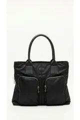 Bolso negro de mano tipo shopper, confeccionado en nylon, con doble asa superior de cuero sintético y dos bolsillos frontales externos con cierre metálico.
