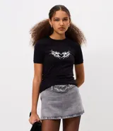 Remera de algodón con elastano, de corte ajustado, manga corta y cuello redondo. Presenta una estampa frontal de corazón con diseño tribal en color blanco sobre fondo negro.