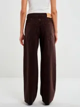 Pantalón de denim de corte ancho y tiro alto, con diseño de cinco bolsillos y cierre frontal con botón y cremallera.