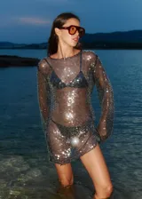 Vestido corto de lentejuelas negras translúcidas con mangas largas.