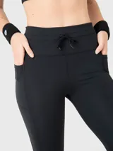 Calza deportiva de tiro alto con cintura elástica ajustable mediante cordón y bolsillos laterales. Diseño ajustado de largo completo en color negro.