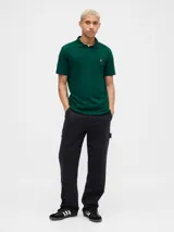 Polo de manga corta color verde oscuro, con cuello clásico, cierre frontal de dos botones y logo del oso Brannan bordado en el pecho.