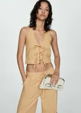 Top corto de cuello halter con cierre frontal mediante lazos decorativos. Presenta un diseño ajustado y sin mangas, confeccionado en una mezcla de fibras naturales.