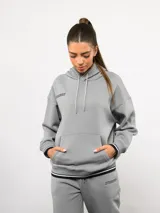 Canguro de felpa con friza, color gris, con capucha, cordones ajustables, bolsillo frontal tipo canguro y detalles de rayas en los puños y el ruedo. Presenta el logo de la marca bordado en el pecho.