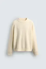 Jersey de punto con textura efecto pelo, corte relajado, cuello redondo y manga larga con acabados en rib.