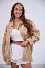 Sobrecamisa de gamuza en color beige, con corte oversize, cierre frontal con botones metálicos a presión, bolsillos frontales y mangas largas con puños abotonados.