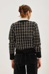 Cardigan de punto en color negro con diseño de cuadros en color beige. Presenta cuello redondo, cierre frontal con botones metálicos y mangas largas con puños anchos en color negro liso.