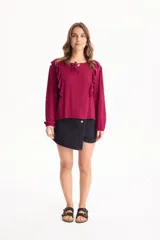 Blusa de viscosa color blanco con escote en V y cordón ajustable, mangas largas y volados decorativos en los hombros.