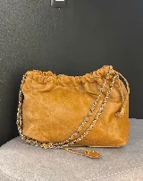 Bolso tipo shopper de cuero negro con diseño acolchado en patrón de rombos. Cuenta con cierre superior fruncido y correa de cadena metálica entrelazada con cuero.