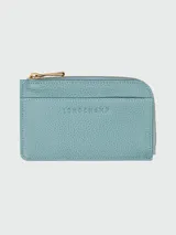 Tarjetero Longchamp de cuero color celeste con cierre de cremallera dorada y logo grabado en el frente.