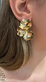 Caravanas de diseño floral con acabado metálico brillante en tono dorado, con forma de pétalos ondulados y centro detallado.