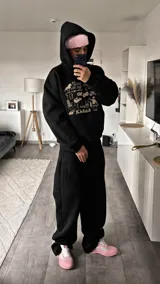 Canguro negro de corte oversize con capucha y bolsillo frontal tipo canguro. Presenta un estampado gráfico en color crema en el pecho que incluye diversos elementos como un caballo, una parrilla, una silla, una motocicleta, una oruga y la palabra KABOA.