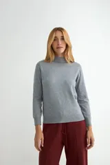 Polera de punto color beige, con cuello alto y mangas largas, de diseño básico y ajuste clásico.