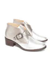 Bota corta de cuero vacuno con acabado metalizado peltre, diseño de solapa cruzada con hebilla metálica lateral y taco cuadrado efecto madera.