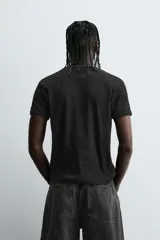 Camiseta gris de corte slim fit, confeccionada en tejido de algodón con elasticidad, cuello redondo y manga corta.