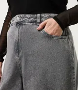 Pantalón de jean de corte recto y tiro medio, color gris con acabado lavado y aplicaciones de brillos distribuidas en las piernas. Cuenta con diseño de cinco bolsillos, cierre frontal con botón y costuras reforzadas.