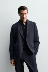 Blazer de corte regular confeccionado en lana de origen italiano. Presenta cuello con solapas de muesca, cierre frontal de un botón, bolsillos laterales con solapa y bolsillo de vivo en el pecho. Incluye abertura central en la espalda y forro interior.