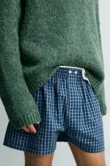 Pack de dos calzoncillos tipo bóxer de popelín de algodón. Uno es amarillo con rayas verticales azules y el otro es azul oscuro con estampado a cuadros. Ambos tienen cintura elástica con efecto doble combinado a contraste y bragueta delantera con botones.