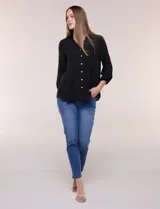 Blusa celeste de silueta suelta y textura liviana, con escote en V, cuello mao y cierre frontal de botones. Cuenta con alforzas verticales en el pecho y mangas tres cuartos con puños elastizados y detalle de galón calado.