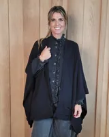 Ruana tejida de algodón con diseño abierto, terminaciones con volados y textura acanalada en los bordes.