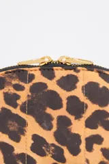 Neceser de nylon con estampado de leopardo, forma de media luna y cierre de cremallera dorado. Presenta un logo metálico de Bimba y Lola en la parte frontal.