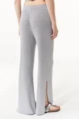 Pantalón gris de tejido de punto confeccionado en lurex. De tiro alto con elástico en la cintura, la pierna se ensancha en el ruedo y cuenta con tajos en los laterales.