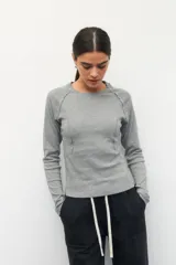 Remera de manga larga color blanco, confeccionada en algodón, con cuello redondo y diseño de costuras decorativas externas que realzan la silueta.