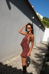 Vestido corto bordó con hilo brillante, escote halter pronunciado y detalle drapeado en el frente. Falda ajustada con fruncidos laterales y terminación con volados.