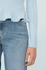 Sweater celeste de tejido de punto con calce al cuerpo, cuello redondo, mangas largas, volado en el ruedo y botones decorativos en el hombro.