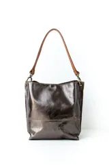 Bolso tipo hobo de cuero con acabado texturizado en tono beige claro, con correa de hombro en cuero liso color suela y herrajes metálicos en bronce envejecido.