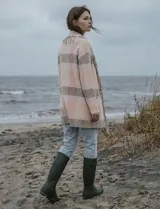 Cárdigan largo de tejido de punto con diseño a cuadros en tonos rosados y beige/gris. Presenta cuello chal y terminaciones con flecos largos en el borde frontal.